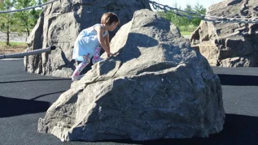 A girl climbing on rock formations at Central Gardens playground