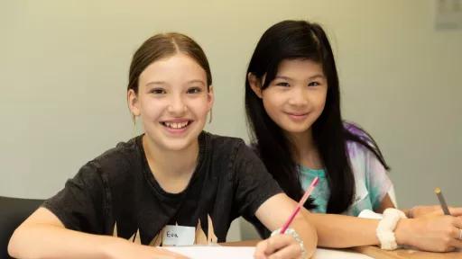 Two young people writing at a table.