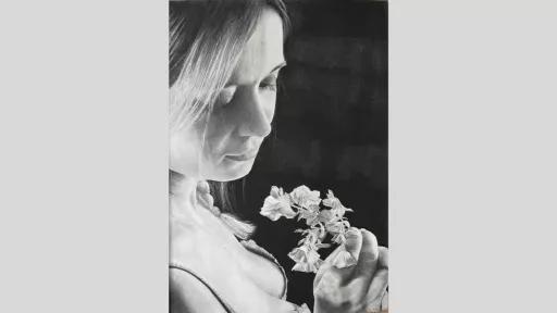 Girl holding a flower and looking down at it.