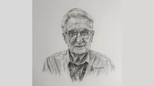 Older man looking straight forward, wearing glasses. He is wearing a lanyard, and his shirt has "remember" and an awareness ribbon embroidered on it.