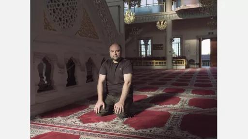 A man kneeling on the carpet in a mosque