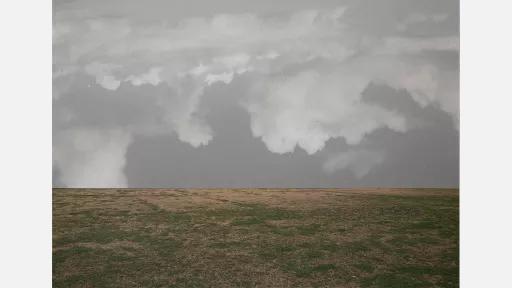 a bare grassy landscape with grey clouds filling the sky