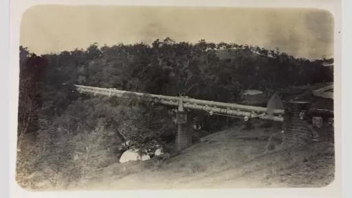 Old and worn photo of pipes bridged across a river