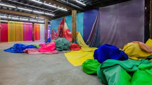 large sheets of canvas painted with bright colours and draped across the walls and piled on the ground