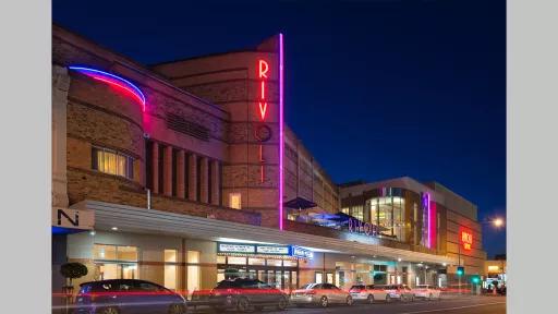 Photo by Ian Spence of the Rivoli theatre at night showing the neon Rivoli sign and lit up entance to the cinema