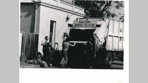 Photo by Elisabeth Frank of garbage collectors loading garbage into the back of a garbage truck