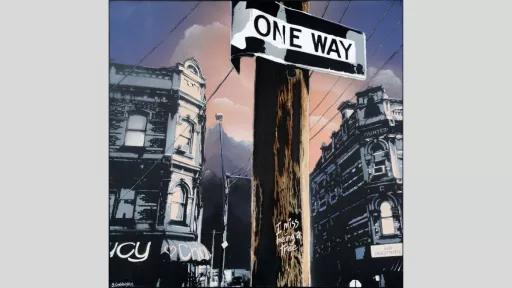 Telephone pole with one-way sign and buildings in background