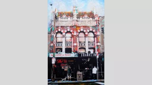 Building with two shopfronts and two people and a dog on footpath