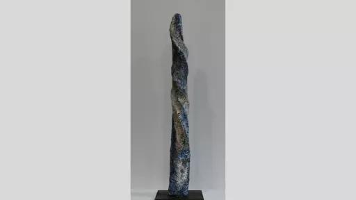 Elongated sculpture with pocked and twisted surface