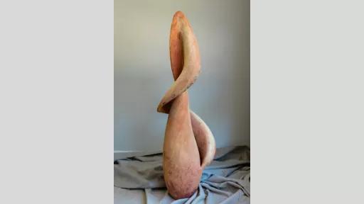 Bulbous, sensual sculpture like an unfurling flower in soft orange colours