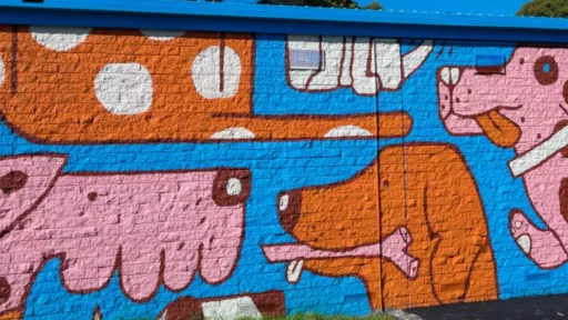 A mural on a building wall showing dogs sitting and playing