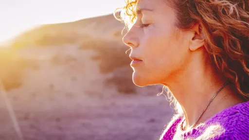 A close up of a person standing on a beach with their eyes closed