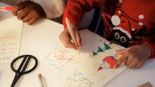 Two children making Christmas cards