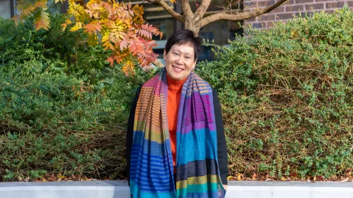 Woman with short black hair smiling and wearing a large scarf