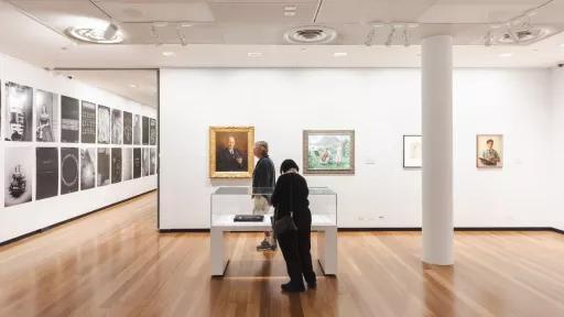 two people looking into a display case containing a bag.