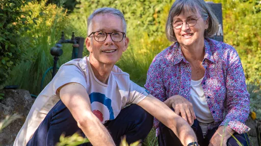 Botanist Tim Entwisle and Lynda Entwisle crouching beside nature strip with tufts of plants in foreground.