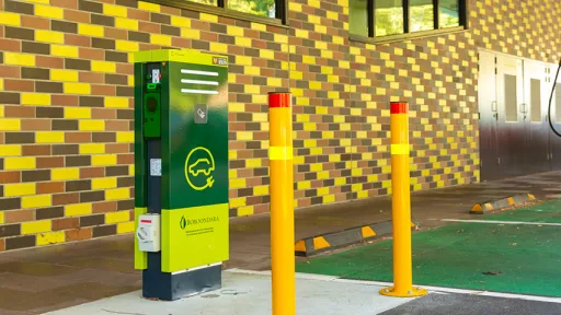 Green metal-clad charger box in parking bay with second white charger in background.