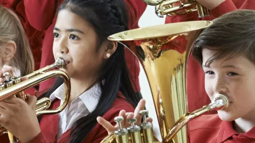 3 primary school children playing large brass instruments