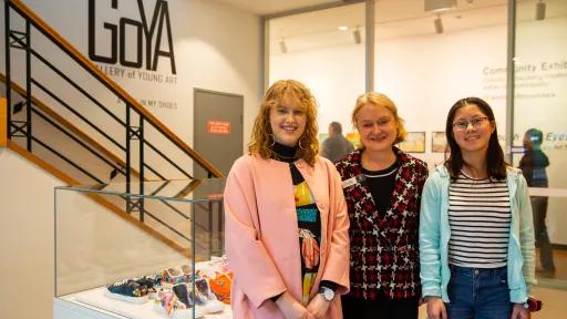 3 people stand in front of a wall signposted Gallery of Young Art