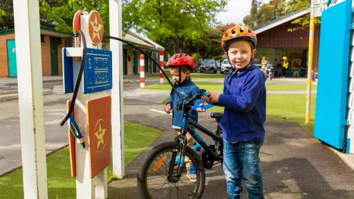 2 young children wearing helmets standing with their bikes at Kew Traffic School