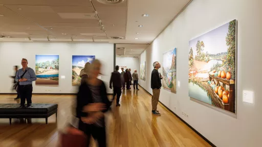 Visitors at an exhibition opening in an art gallery.