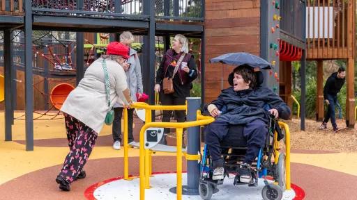 a person in a wheelchair being pushed around on the merry-go-round.