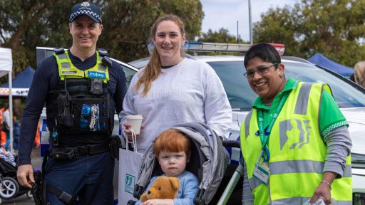 4 adults and a child smiling at the camera. One is wearing a police uniform, and one is wearing a high vis safety vest