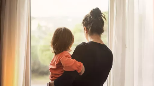 Mother holding child looking out of window