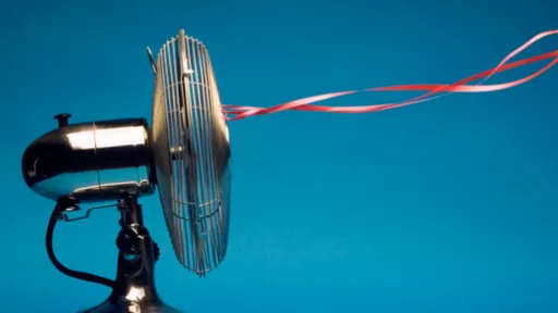 Copper-coloured electric fan blows air - with red ribbons attached to fan floating in the air