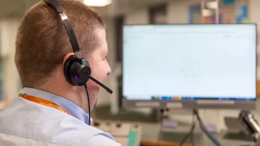 A person is sitting at a computer screen with a call centre headset on