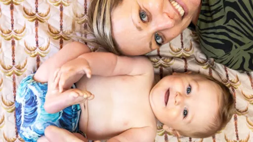 Baby wearing reusable nappy lies beside mother