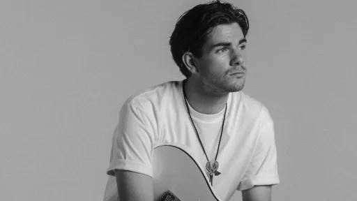 Young man sitting holding a guitar