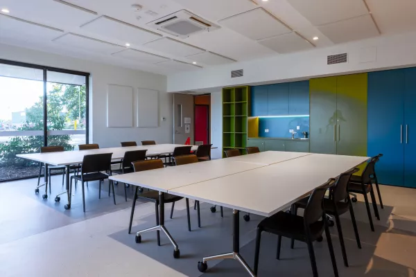 A meeting room with large tables and a small kitchen