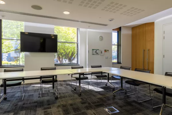 A carpeted meeting room with a TV screen and windows